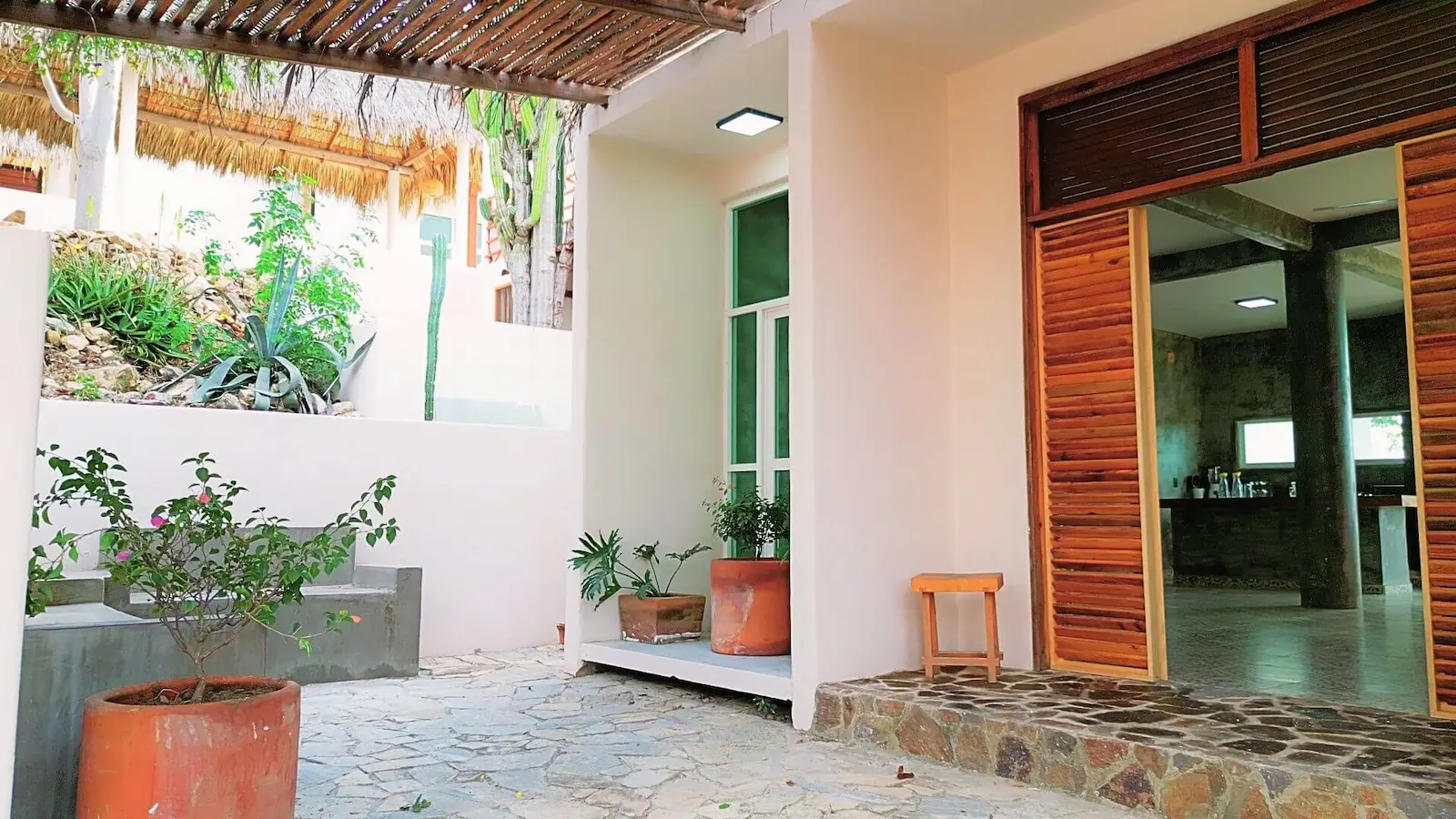 Entrance to SOL Suite with palm roof and stone floors / Entrada a Suite SOL con techo de palapa y pisos de piedra en CasaInspira